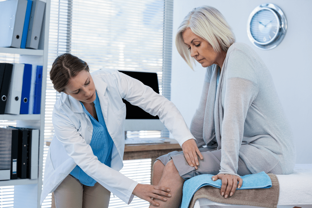 Doctor examining patients with knee joint arthropathy